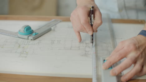 Close-up-of-architect-hands-making-house-blueprint-in-the-office-near-window.-Concept:-architecture-blueprint-house-paper-work