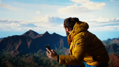 un escalador descuidado distraído por su teléfono inteligente está cayendo en la cima de una montaña