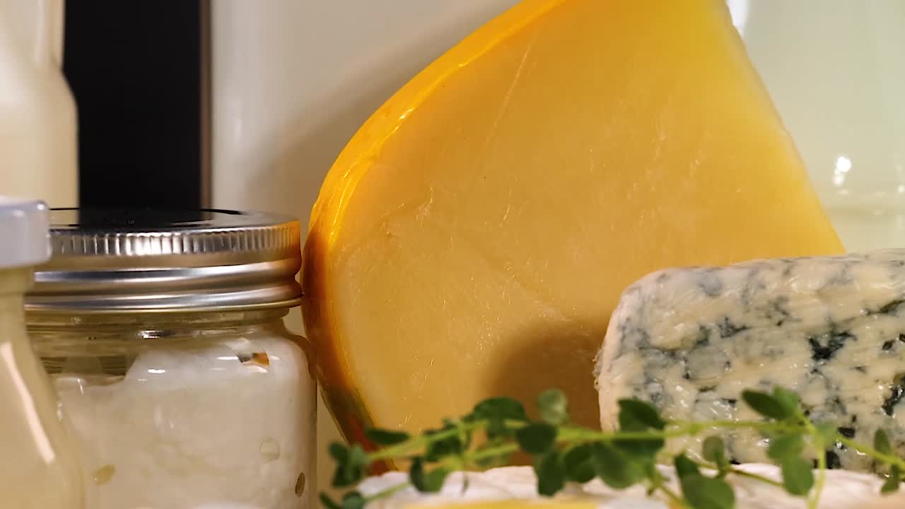 A selection of cheeses and sealed jars displayed on a wooden board.