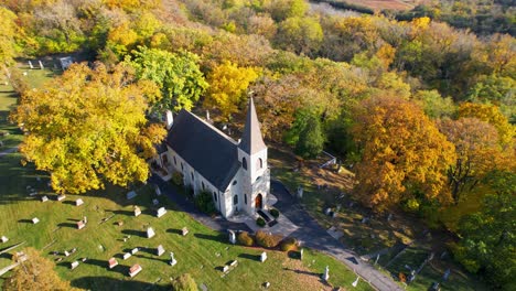 small country catholic church and cemetery with bright colorful autumn trees drone