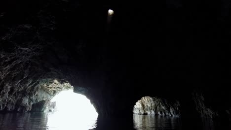 unique atmosphere inside a sea cave with a ray of light coming down from a hole in the ceiling, vis island, adriatic sea, croatia