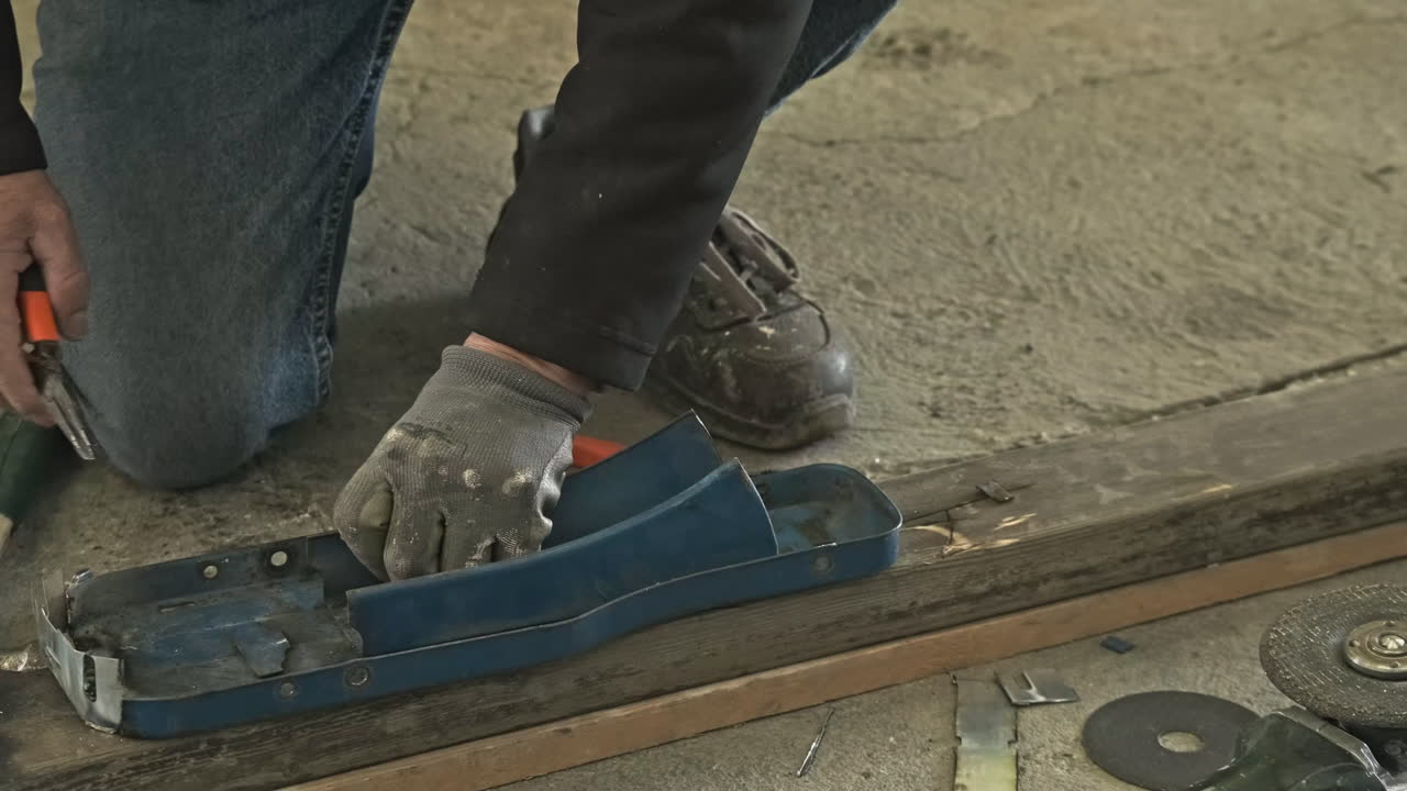 Primo piano di un operaio specializzato che lavora su un pezzo di metallo con delle pinze in un'officina industriale - slow motion, inquadratura statica.