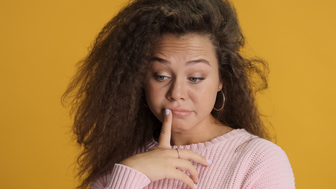 Thoughtful Caucasian curly haired woman in front of the camera.