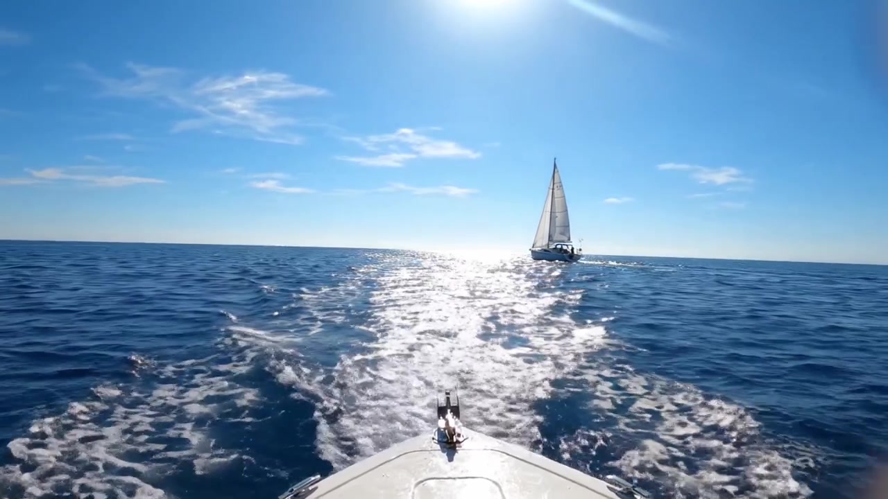 A Serene Day on the Open Sea: Captivating Views of a Sailboat Cutting Through Sparkling Waters Under a Brilliant Sunlight During Perfect Sailing Conditions