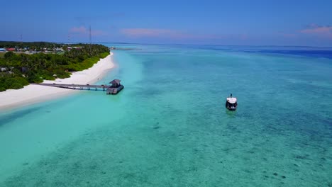 a view of a resort hotel and its wood deck on the turquoise sea in the maldives, drone footage with camera tilt motion on a clear day