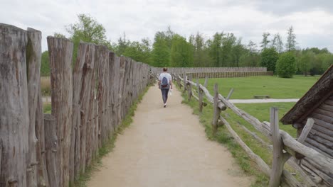 A-woman-in-her-thirties-strolls-along-the-ancient-walls-of-Biskupin,-Poland,-immersing-herself-in-the-timeless-atmosphere-of-the-historic-settlement