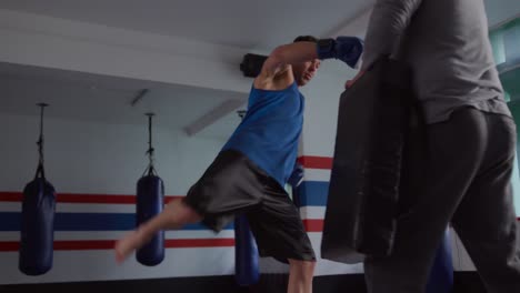 caucasian man training with coach in boxing gym