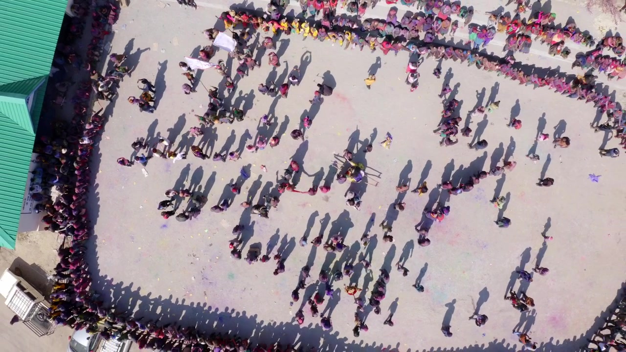 Topputsikt over folk som feirer Holi, Fargefestivalen, i Sangla, Himachal Pradesh, India – dronebilde.