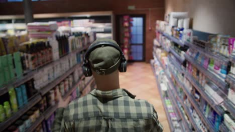 rear view of a guy with headphones listening to the music and funny dance wearing plaid shirt