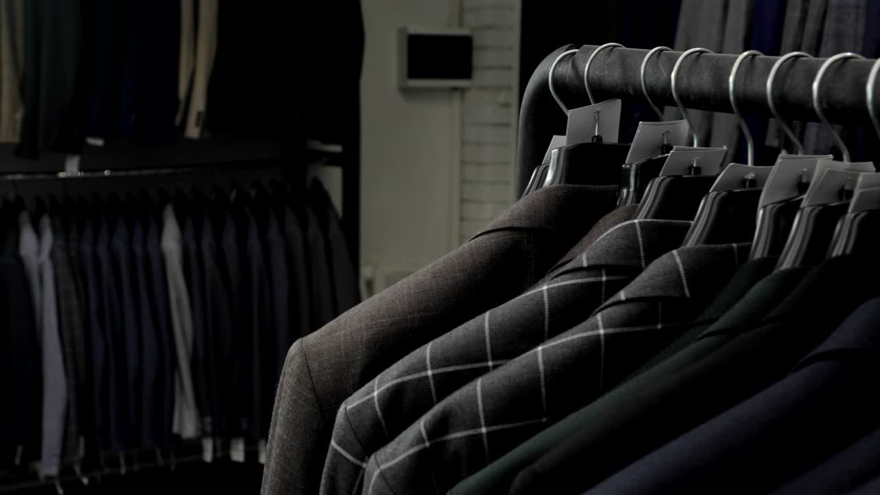 Men's suit at tailor's shop. Men's hands choose a jacket in their wardrobe. Male choosing
