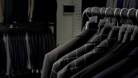 men's suit at tailor's shop. men's hands choose a jacket in their wardrobe. male choosing
