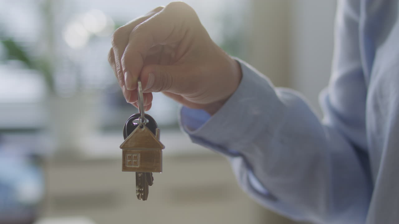 Hand of Real Estate Agent Holding House Keys in Office