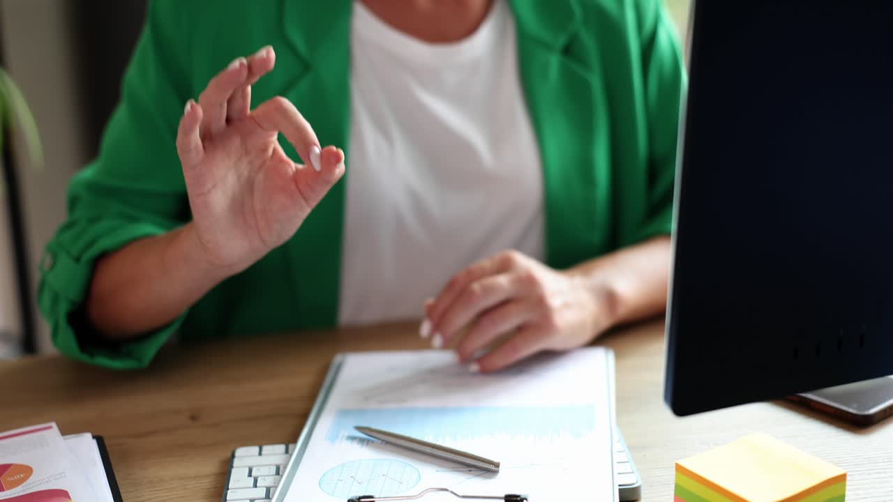 Business woman showing ok sign at her desk