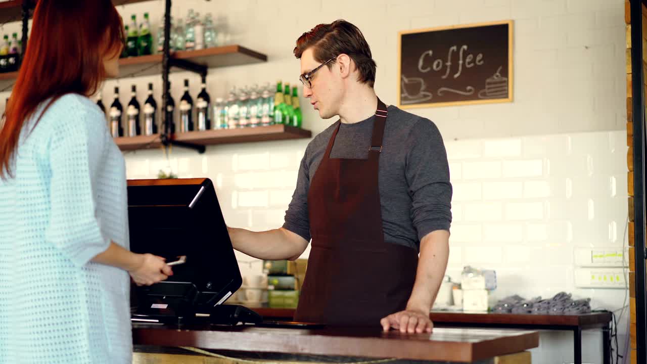 예쁜 젊은 여자가 커피에서 커피를 사서 스마트폰으로 지불하고 콘택트리스 결제를 하고 있습니다. 현대 기술과 은행 개념입니다.