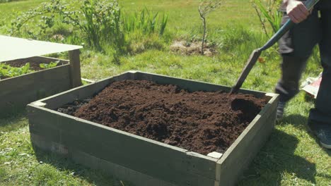 leveling compost with shovel in raised garden bed