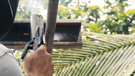 soldador profesional que emplea una máquina de soldadura industrial para unir dos piezas de metal creando una estructura metálica como parte de su trabajo diario en una pequeña empresa local