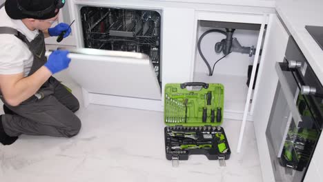 professional repair of dishwashers a repairman is repairing a dishwasher in the kitchen