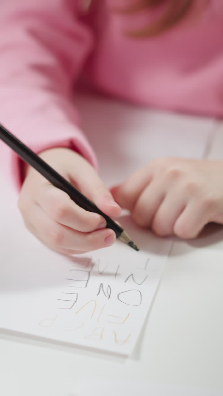 African-American tutor shows cards and little girl pupil writes digit names in English language on paper at home lesson closeup slow motion
