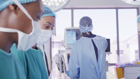 Video-of-three-diverse-female-surgeons-talking-during-operation-in-theatre,-copy-space