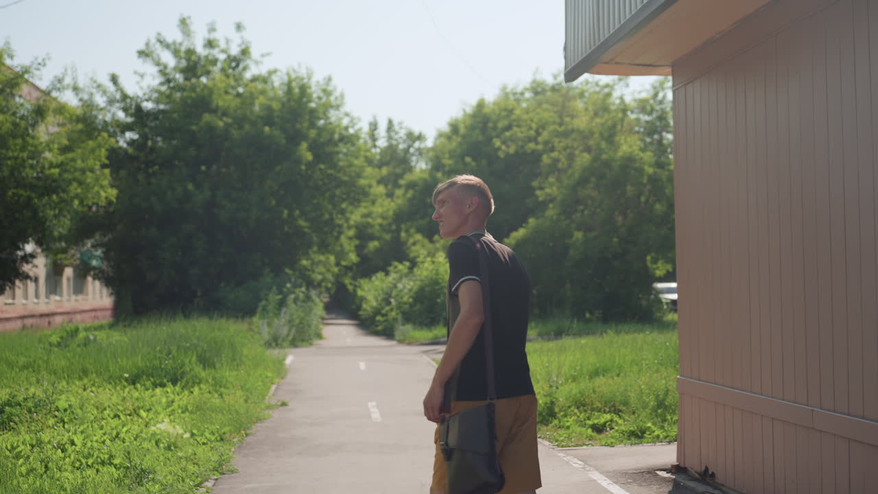 Youthful Pedestrian Calmly, Young White Individual Wandering Leisurely Along Bright Grassy Trail, An Adolescent Man With Fair Skin Walking Slowly Through Tranquil Sunlit Neighborhood Setting