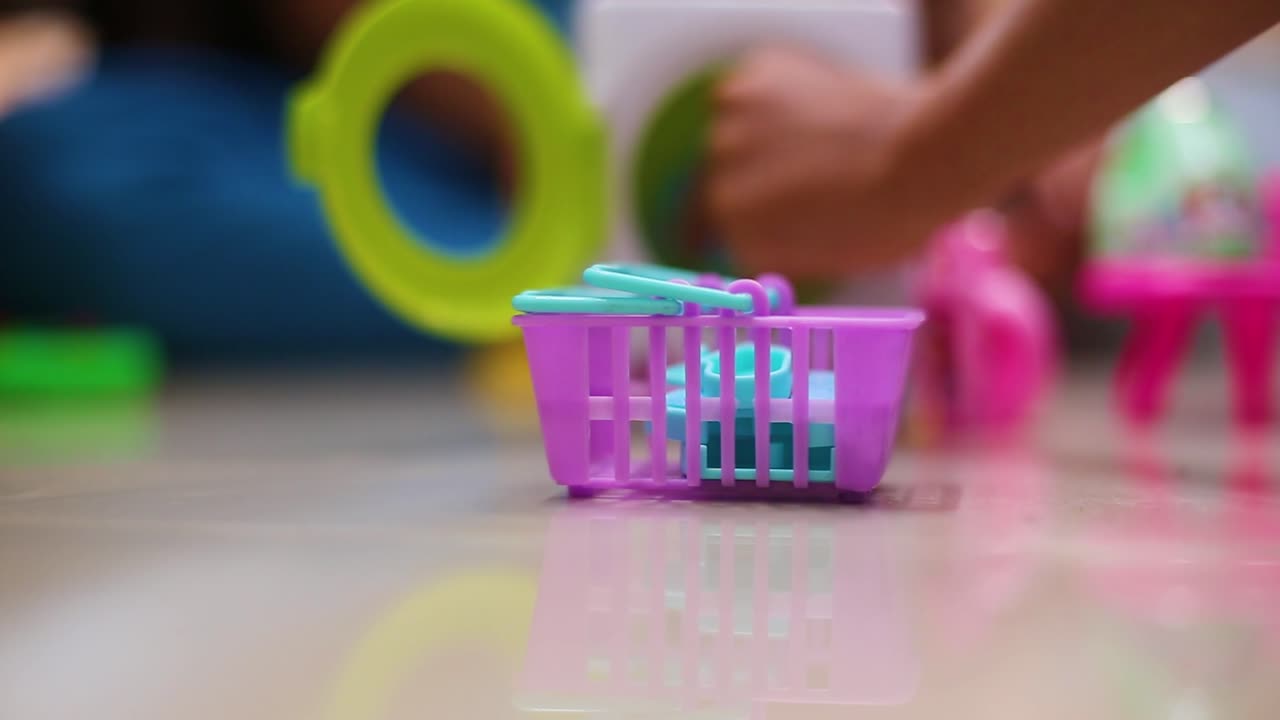 Criança pequena adorável brincando com máquina de lavar de brinquedo e roupas dentro de casa.