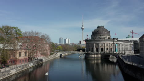 Antena:-Vuelo-Lento-Sobre-El-Río-Spree-En-Berlín,-Alemania-Con-Vistas-A-La-Torre-De-Televisión-Alexanderplatz-En-Un-Hermoso-Día-De-Cielo-Azul