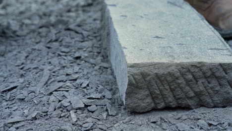 handheld closeup shot of a person using a handheld pick to shape the edge of cancagua stone slab, in the city of ancud, chiloe island