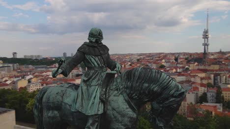 aerial drone footage capturing the iconic statue of jan žižka at vítkov national monument in prague. the statue commemorates the legendary czech general overlooking the city's landscape.