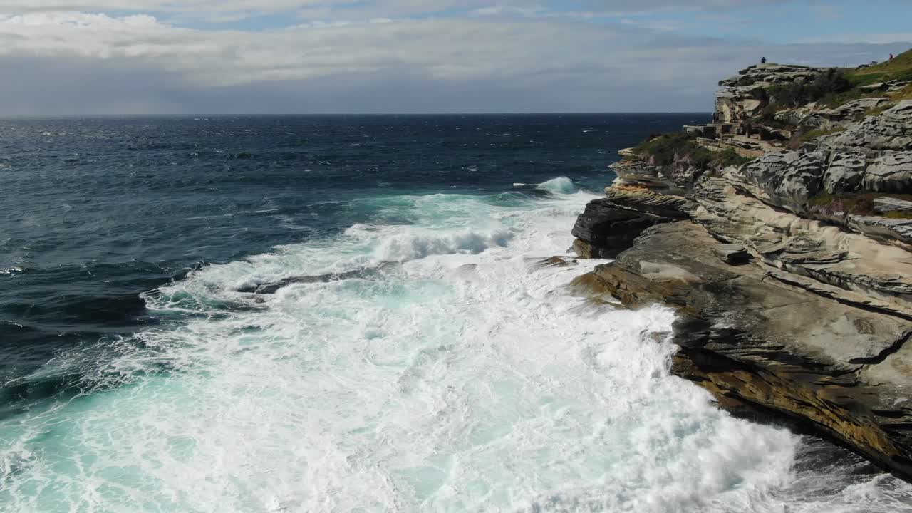 Rocky coast near Bondi beach with stormy waves crashing on cliff in Australia