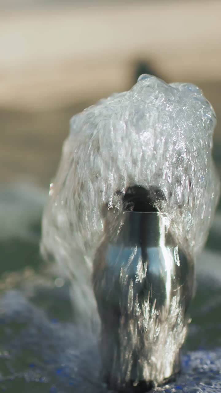 mano de un hombre con abrigo negro interactuando con el agua de manantial que fluye de una pequeña fuente, destacando la superficie del agua burbujeante, los reflejos y el movimiento dinámico en un entorno al aire libre