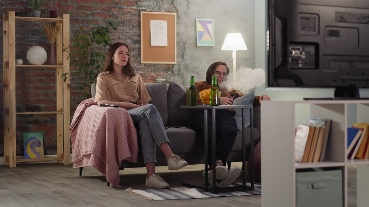 hombre fuma vape sentado con una mujer en un juego de fútbol en el piso