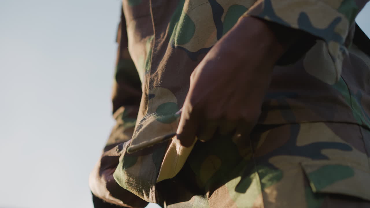 Military Personnel Fastening Canteen Strap, Soldier Attaching Water Container To Belt During Field Exercise, Military Individual Ensuring Water Canteen Is Secure For Field Hydration And Readiness