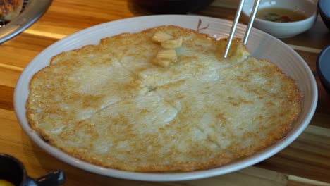 pajeone - hands putting onion taking a slice of traditional korean pizza made from rice flour and vegetables