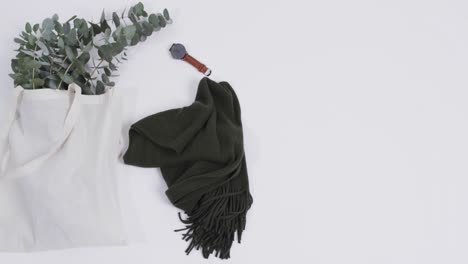 Video-of-white-canvas-bag-with-plant,-scarf,-watch,-copy-space-on-white-background