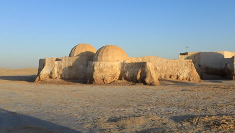 sunrise over star wars igloo-like set in a desert, casting long shadows