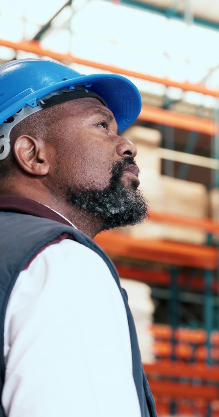 Warehouse Manager Wearing Hard Hat Looking Up at Shelving
