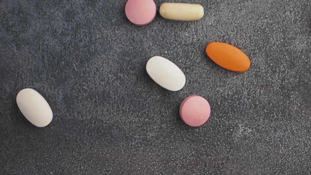 Different colored pills on a dark surface