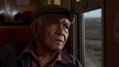 elderly man looking out of a train window