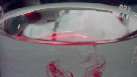 red liquid dropping in flask. closeup blood drops flowing in water