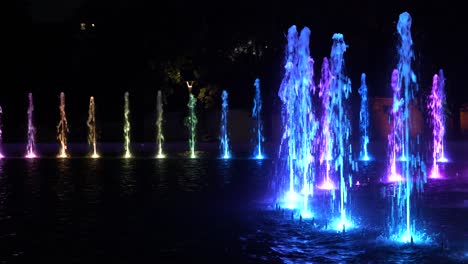 Nachts-Beleuchteter-Brunnen-Im-Stadtpark,-Abstrakte-Lichter-Mit-Wechselnden-Farben-Aus-Mehreren-Düsen-Im-Kreis