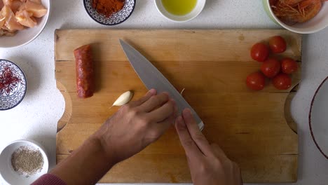 video de cocina de arriba hacia abajo, manos masculinas pelando ajo con el dorso del cuchillo