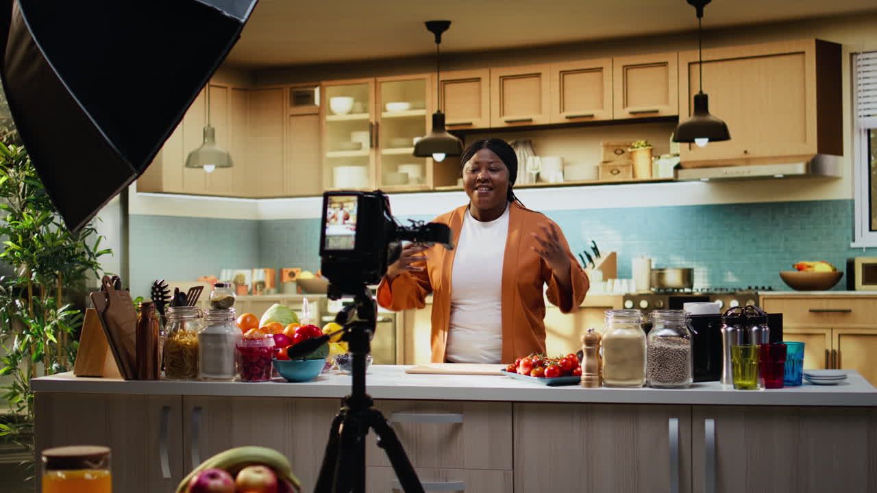 Dietro le quinte di una donna che registra un vlog di preparazione pasti con treppiede in cucina
