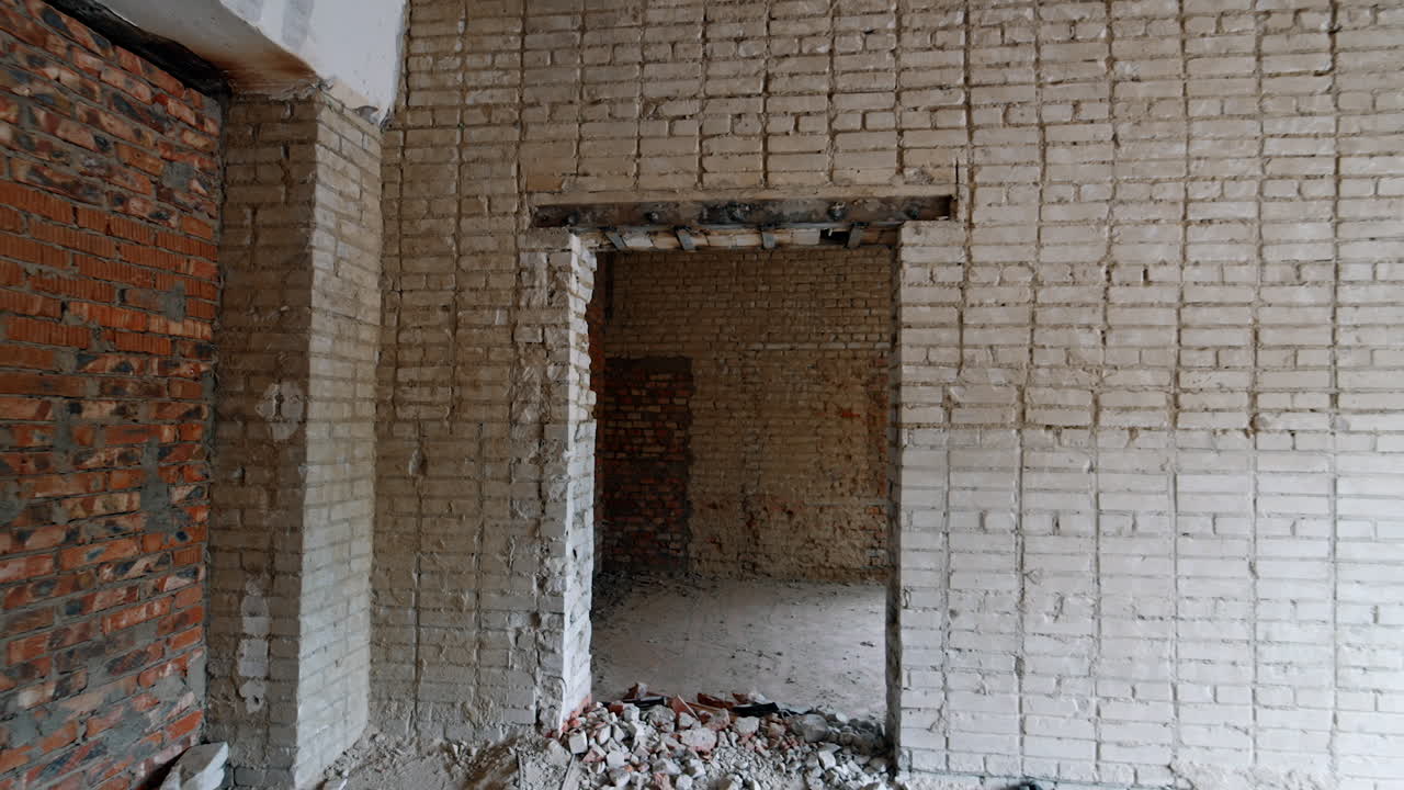 Bare walls of diverse color of bricks. Walking by the rooms of the house prepared for renovation.
