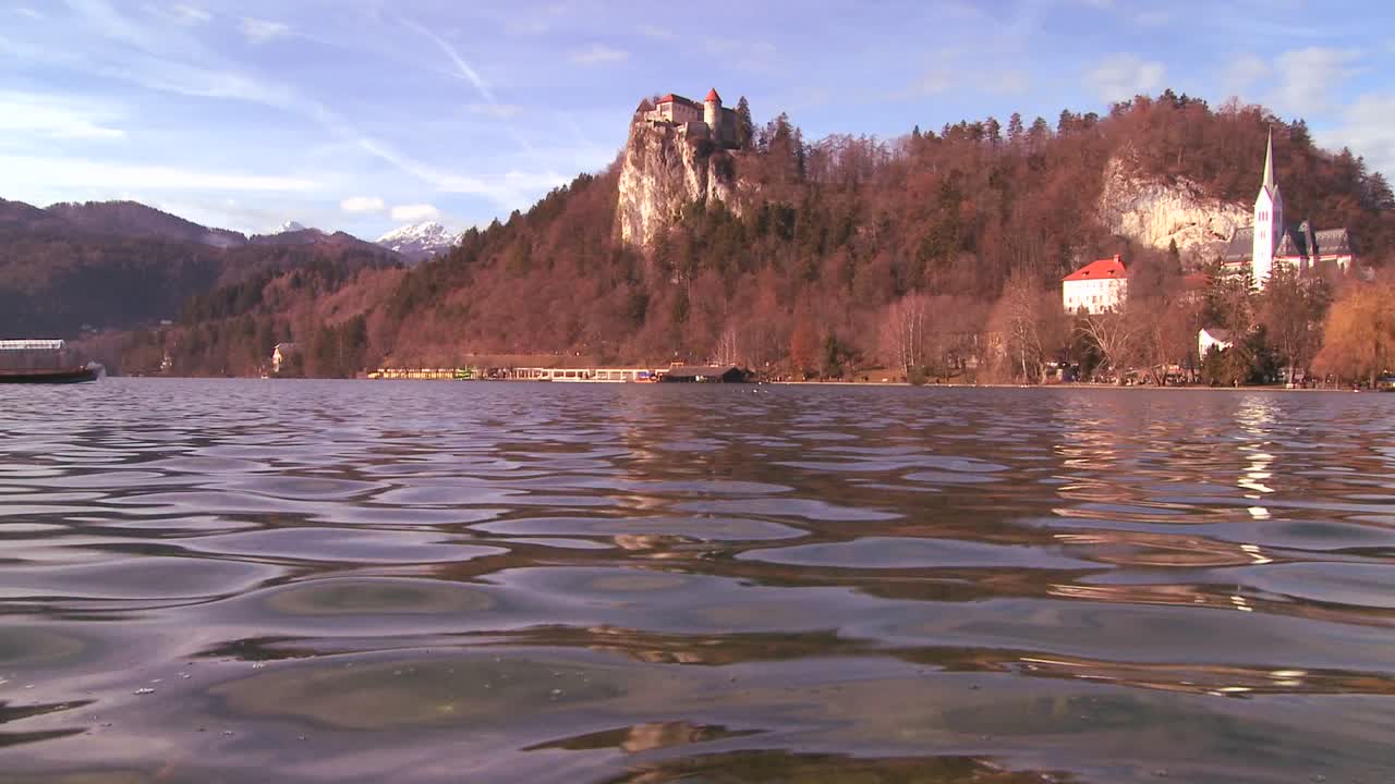 슬로베니아 블레드 호숫가에 있는 아름다운 중세 성과 교회를 보트가 지나갑니다.