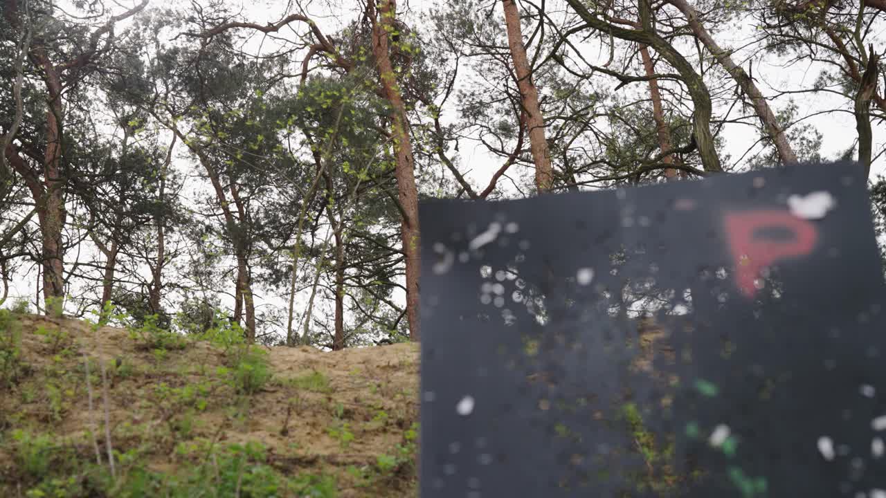 Target wall with holes at Olesko shooting range with green tree background