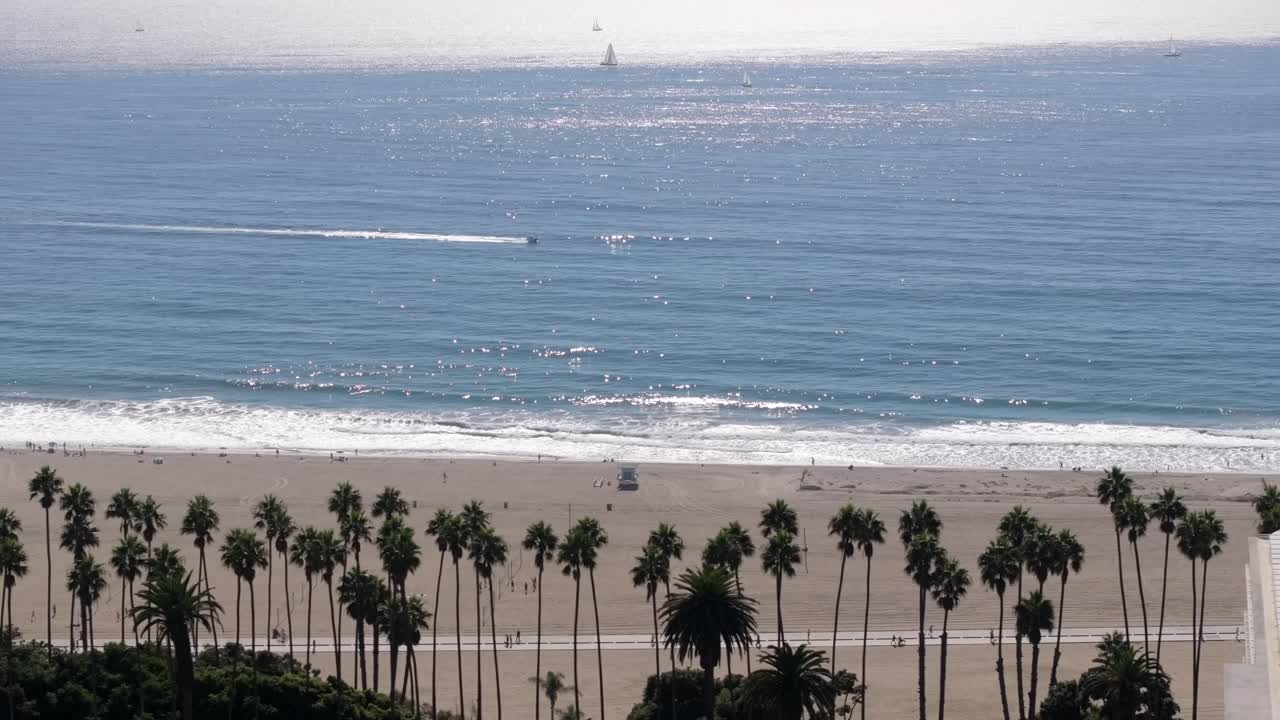 산타 모니카 해변의 공중 풍경은 나무로 둘러싸여 있으며, 스피드보트가 바다를 가로질러 항해하고 있습니다.