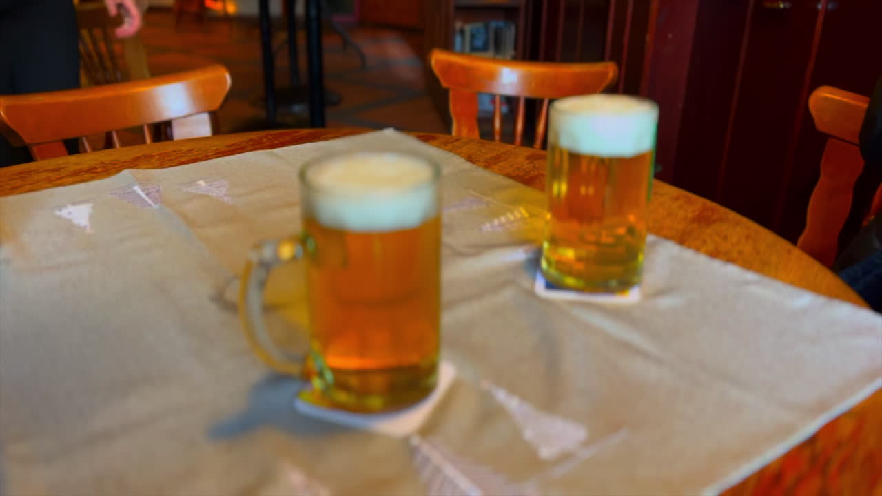 la camarera sirve algunos bocadillos en una mesa con 2 pintas de cerveza rubia
