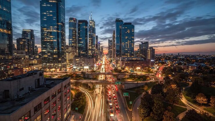 Splendido Paesaggio Urbano in Transizione dal Giorno alla Notte, che mostra uno skyline cittadino vivace con flusso di traffico e grattacieli luminosi sotto un cielo drammatico.