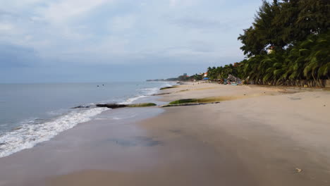 Aerial,-low-flyover-tropical-beach-with-giant-aqua-bags-on-shore-to-prevent-erosion-caused-by-rising-sea-levels