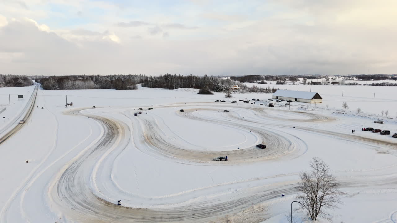 Aerial view rising around cars driving on a rural ice track, winter day